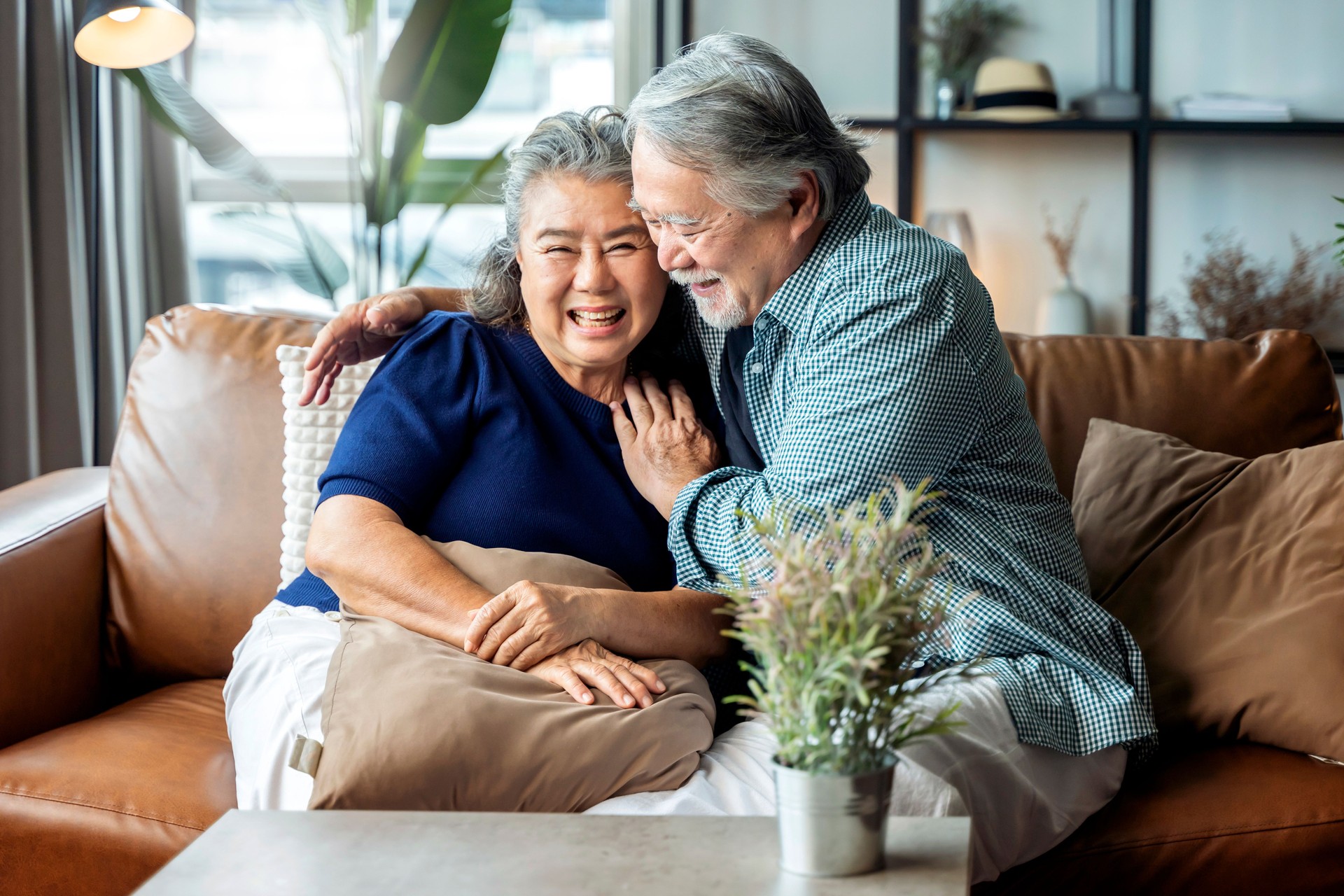 old senior asian retired couple enjoy talking conversation together on sofa with happiness laugh smile and joyful at home,asian old mature adult stay home quarantine period concept